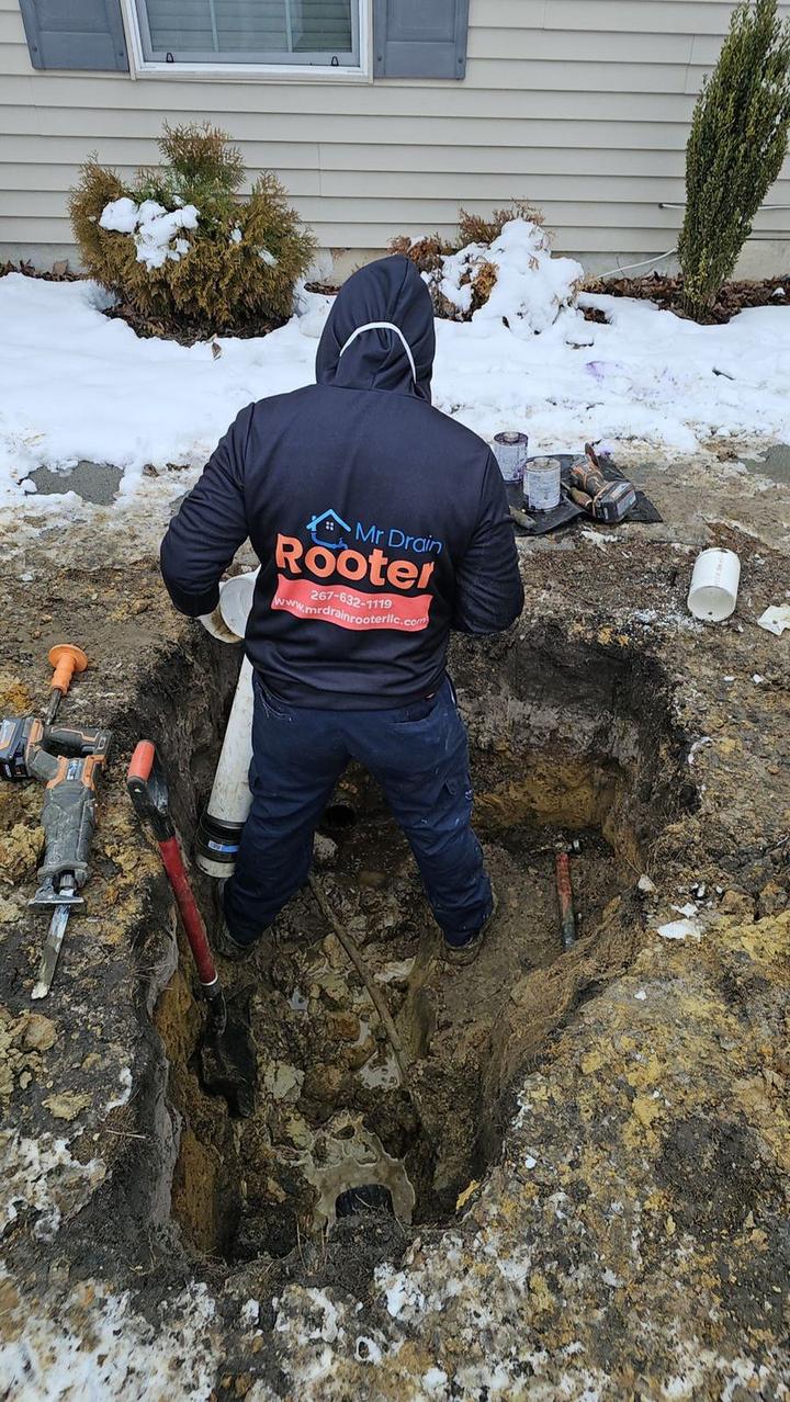 Mr Drain Rooter technician working in an excavated pipe trench