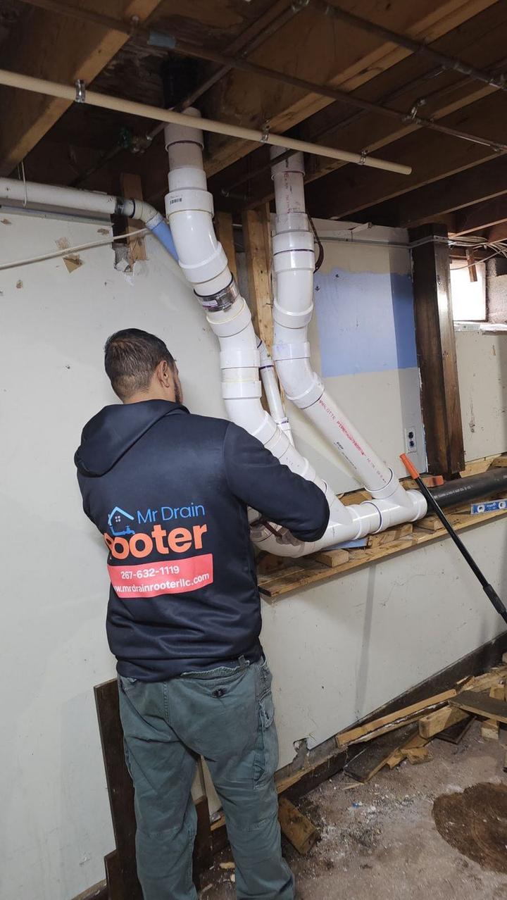 Mr Drain Rooter technician working on drain pipes in a basement